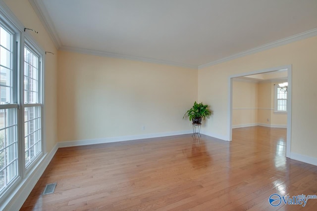 empty room featuring light wood finished floors, visible vents, baseboards, ornamental molding, and an inviting chandelier