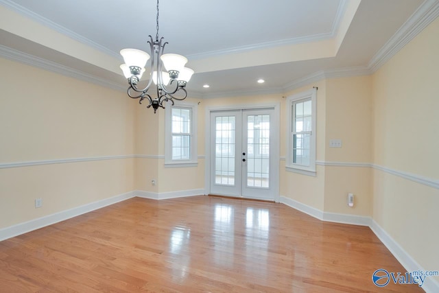 interior space with ornamental molding, french doors, baseboards, light wood finished floors, and a raised ceiling