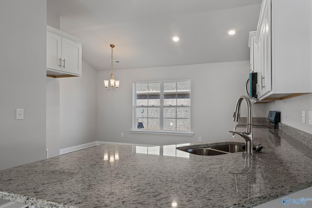 kitchen with white cabinetry, decorative light fixtures, light stone countertops, and sink