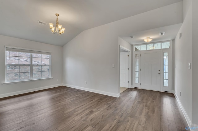 foyer with lofted ceiling, dark wood-type flooring, and a notable chandelier