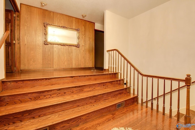 staircase with wood-type flooring and wood walls