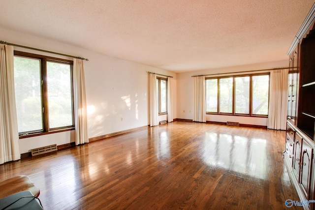 unfurnished living room with hardwood / wood-style flooring, plenty of natural light, and a textured ceiling