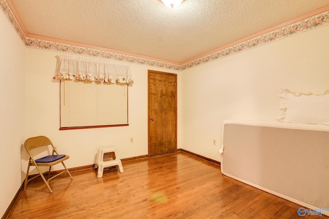 unfurnished room with hardwood / wood-style flooring, ornamental molding, and a textured ceiling