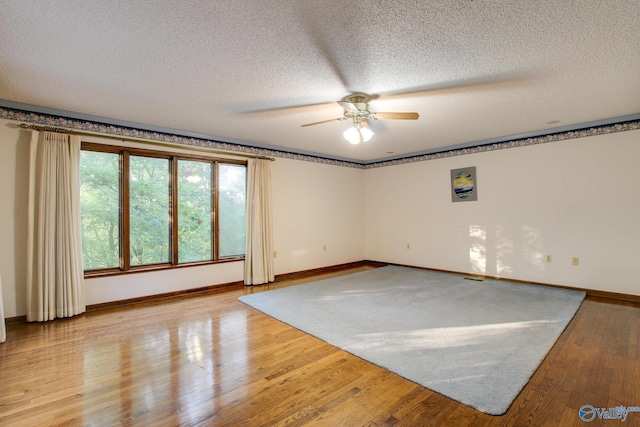 unfurnished room with ceiling fan, a textured ceiling, and light wood-type flooring