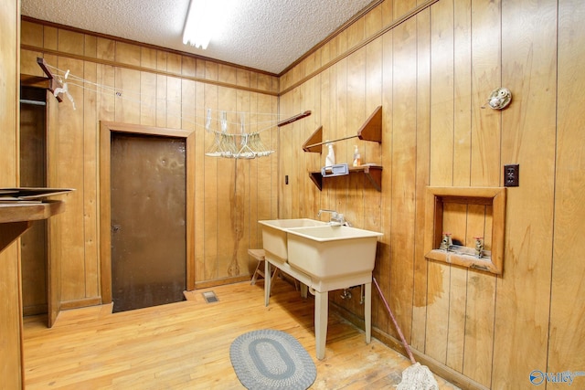 interior space with crown molding, wooden walls, hardwood / wood-style floors, and a textured ceiling