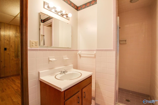 bathroom with vanity, wood-type flooring, tile walls, and walk in shower