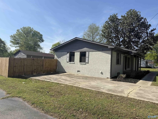 view of home's exterior featuring fence, crawl space, a patio, a lawn, and brick siding
