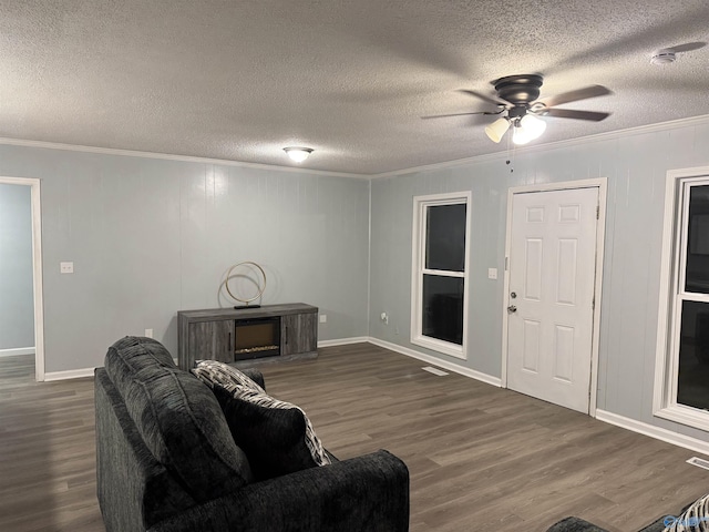 living room with dark wood-type flooring, a textured ceiling, and crown molding