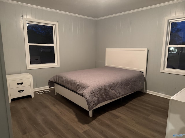 bedroom featuring dark wood-style flooring, ornamental molding, visible vents, and baseboards