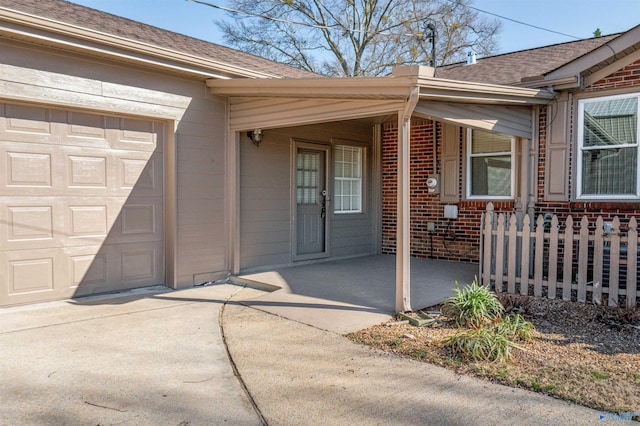 view of exterior entry featuring brick siding, a shingled roof, a porch, a garage, and driveway