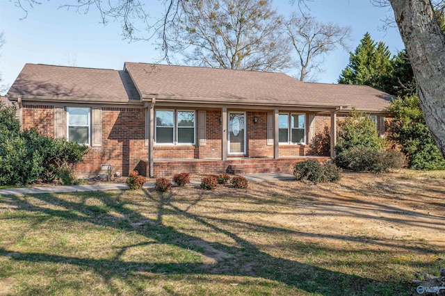 single story home featuring brick siding, a shingled roof, and a front lawn