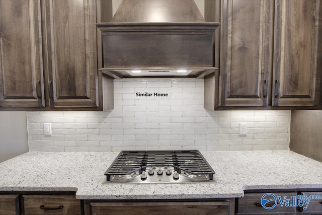 kitchen with light stone countertops, stainless steel gas cooktop, dark brown cabinetry, and decorative backsplash