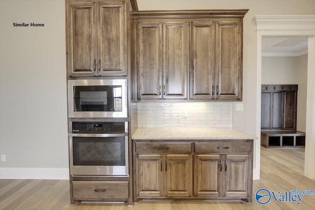 kitchen featuring stainless steel appliances, tasteful backsplash, light stone counters, and light hardwood / wood-style flooring