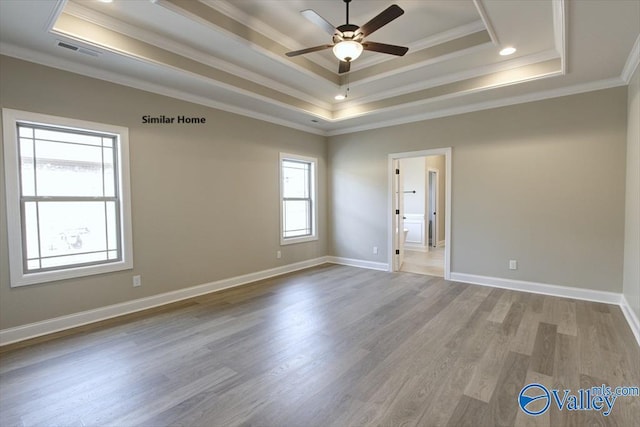 empty room with crown molding, hardwood / wood-style floors, ceiling fan, and a tray ceiling