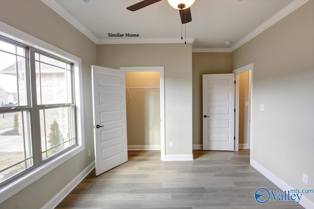 unfurnished bedroom featuring multiple windows, crown molding, and light wood-type flooring