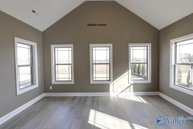 unfurnished room with hardwood / wood-style flooring, high vaulted ceiling, and a wealth of natural light