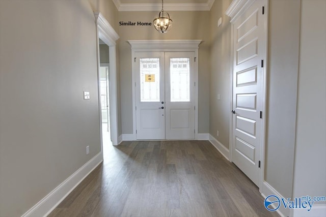 foyer entrance with an inviting chandelier, wood-type flooring, ornamental molding, and french doors