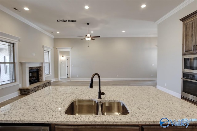 kitchen with stainless steel appliances, light stone countertops, sink, and a center island with sink