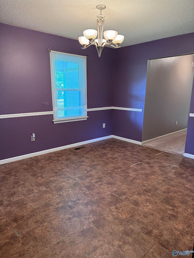 unfurnished room featuring a textured ceiling and a chandelier