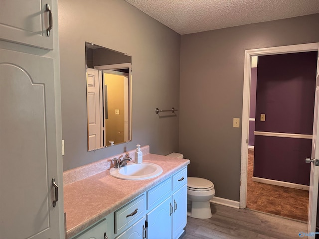 bathroom with wood-type flooring, toilet, a textured ceiling, and vanity