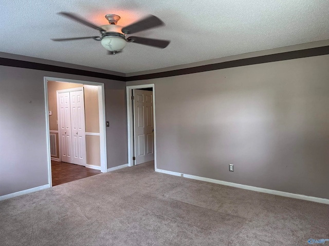 unfurnished bedroom with a textured ceiling, dark carpet, and ceiling fan