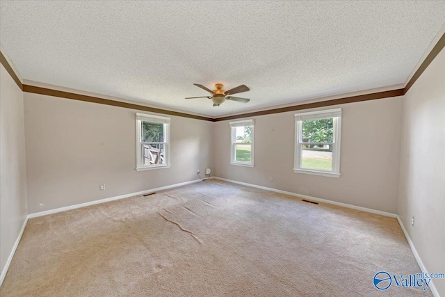 carpeted spare room with a textured ceiling, crown molding, and ceiling fan