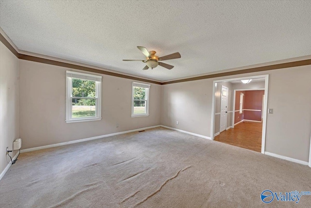 spare room with a textured ceiling, light colored carpet, ceiling fan, and ornamental molding