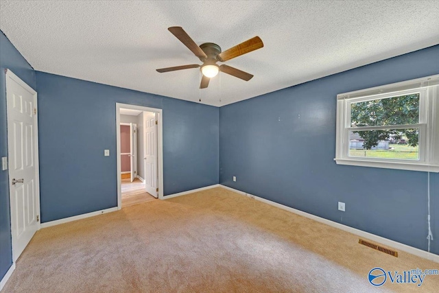 carpeted spare room with a textured ceiling and ceiling fan