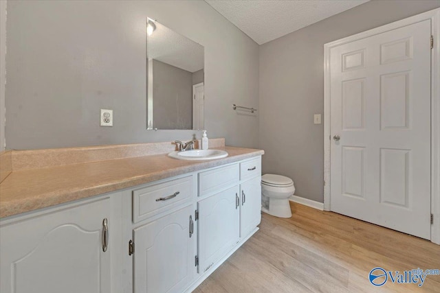 bathroom featuring hardwood / wood-style floors, toilet, a textured ceiling, and vanity