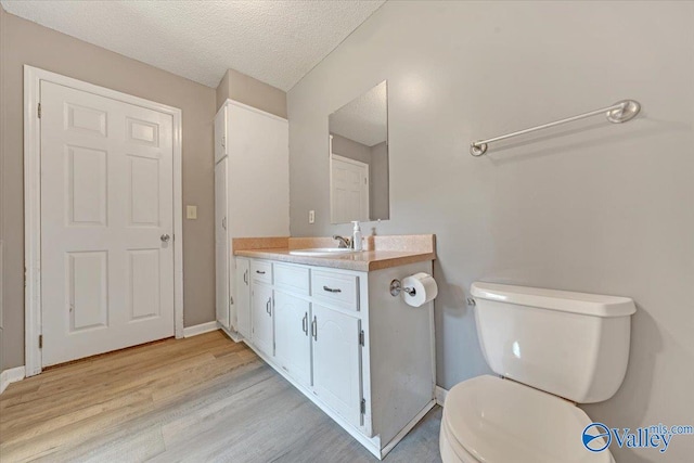 bathroom with toilet, hardwood / wood-style flooring, a textured ceiling, and vanity