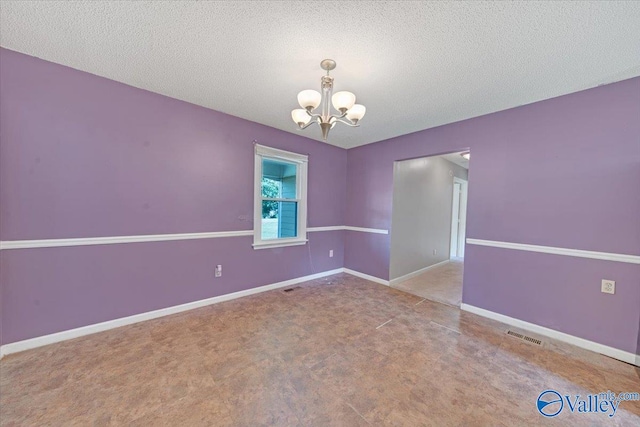 empty room featuring a textured ceiling and an inviting chandelier