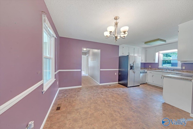 kitchen with white cabinetry, a chandelier, a textured ceiling, sink, and appliances with stainless steel finishes