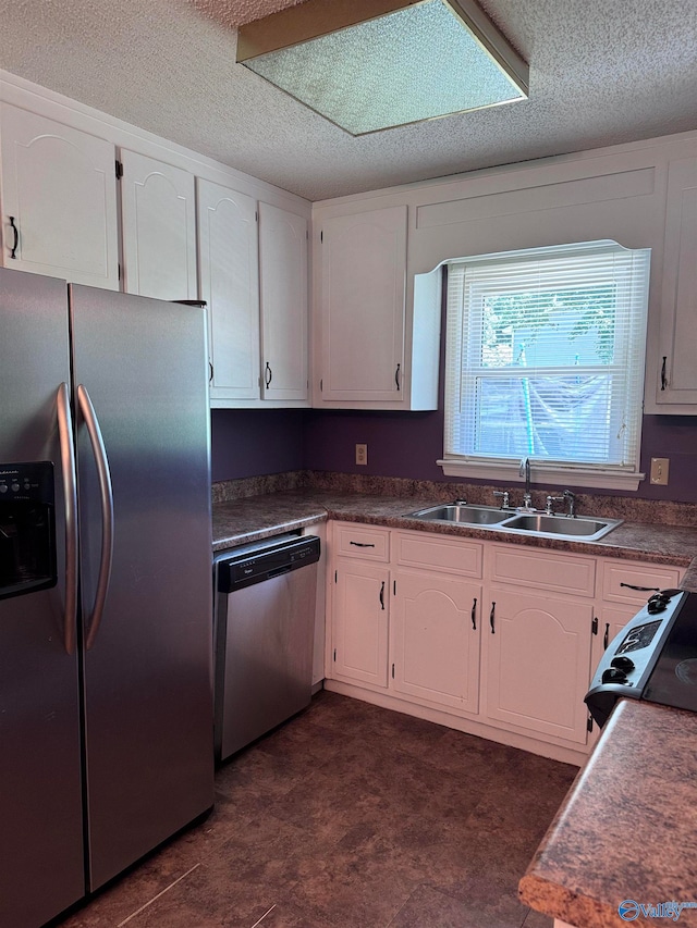 kitchen featuring white cabinets, stainless steel appliances, a textured ceiling, and sink