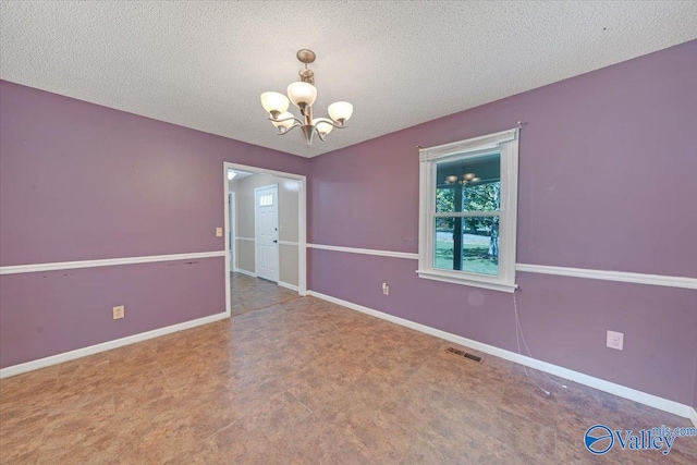 unfurnished room featuring a textured ceiling and an inviting chandelier