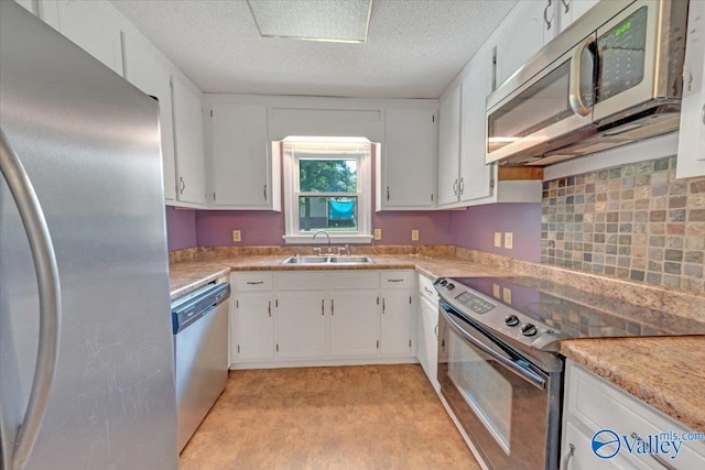 kitchen with appliances with stainless steel finishes, white cabinetry, a textured ceiling, and sink