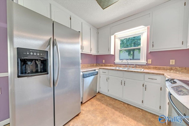 kitchen featuring appliances with stainless steel finishes, a textured ceiling, white cabinetry, and sink