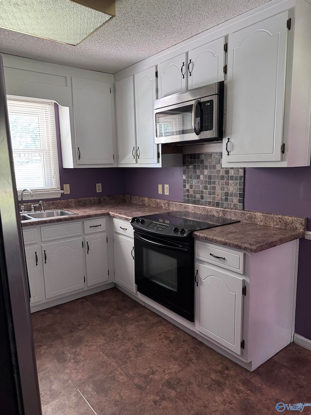 kitchen with backsplash, stainless steel appliances, white cabinetry, sink, and a textured ceiling