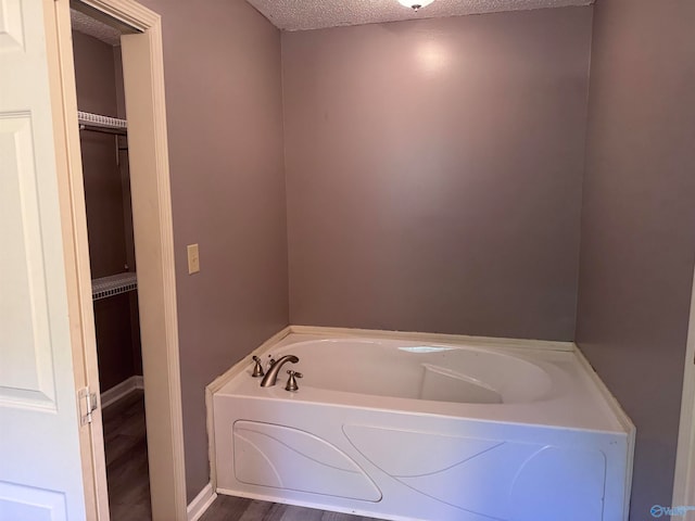 bathroom with a bath, hardwood / wood-style flooring, and a textured ceiling