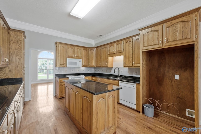 kitchen featuring white appliances, a kitchen island, a sink, ornamental molding, and backsplash