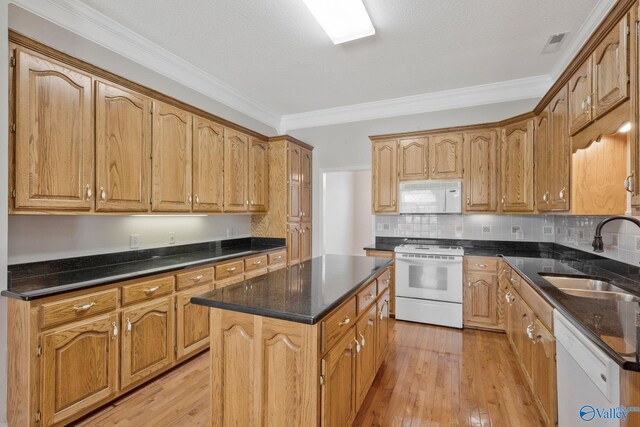 kitchen featuring light wood finished floors, white appliances, a sink, and crown molding