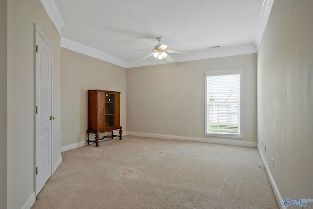 empty room with ornamental molding, light carpet, baseboards, and a ceiling fan