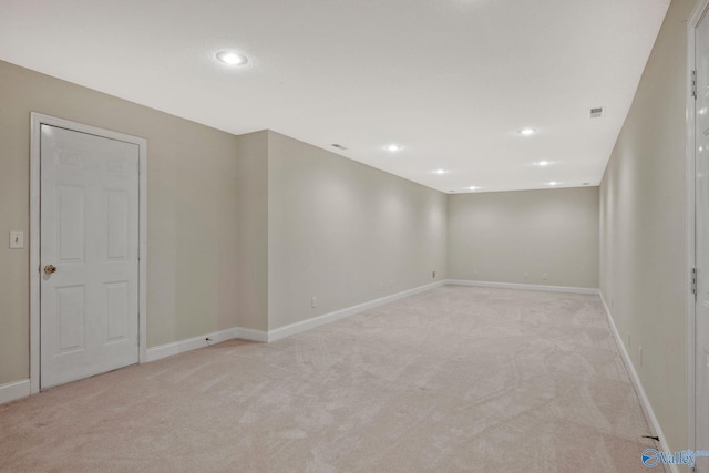 spare room featuring light carpet, recessed lighting, and baseboards