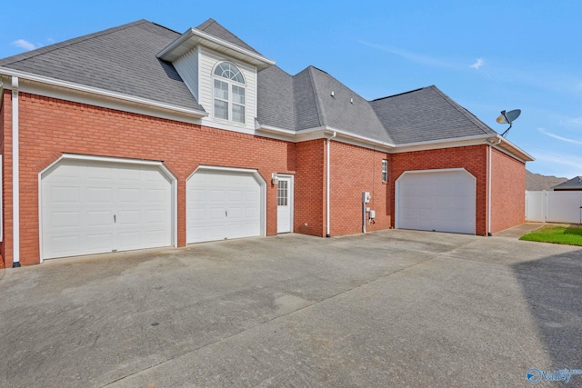 view of front of home featuring concrete driveway, brick siding, roof with shingles, and an attached garage