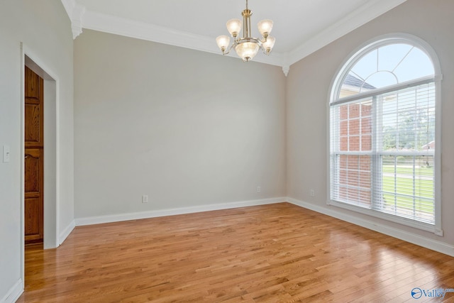 unfurnished room featuring ornamental molding, baseboards, light wood finished floors, and an inviting chandelier