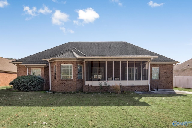 rear view of property with a lawn and a sunroom