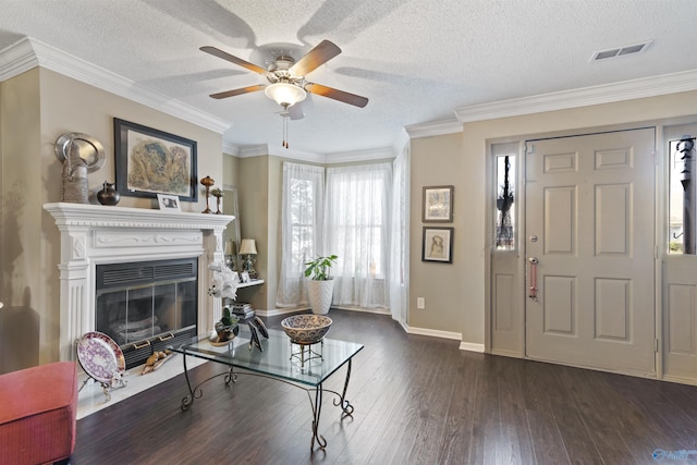 living area with visible vents, ceiling fan, ornamental molding, a textured ceiling, and dark wood-style flooring