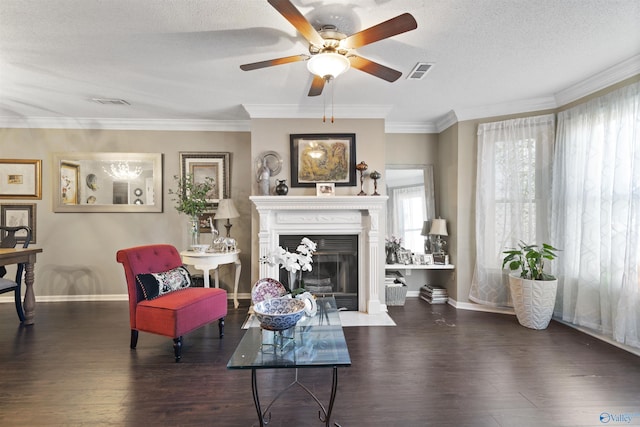 living area featuring wood finished floors, visible vents, ceiling fan, a textured ceiling, and crown molding