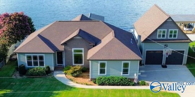 view of front of home with a water view, an attached garage, a front lawn, and concrete driveway