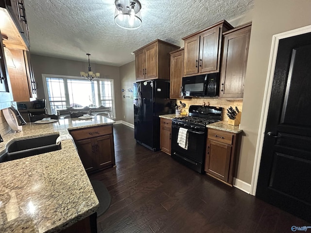 kitchen with dark wood-style flooring, tasteful backsplash, an inviting chandelier, a peninsula, and black appliances