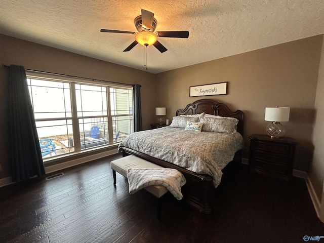 bedroom with a textured ceiling, dark wood-style flooring, a ceiling fan, visible vents, and baseboards